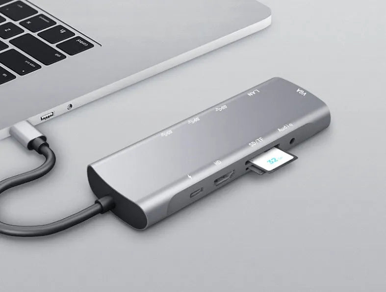 Grey aluminium alloy USB-C docking station with HDMI, VGA, USB ports, and a card reader.