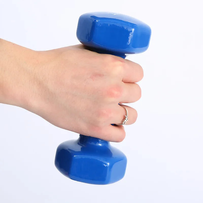 A set of bright red, blue, and green plastic fitness dumbbells with glossy finish on a wooden floor.