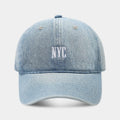 A light blue denim peaked cap with a dome crown, adjustable strap, and decorative white English letters on the front.