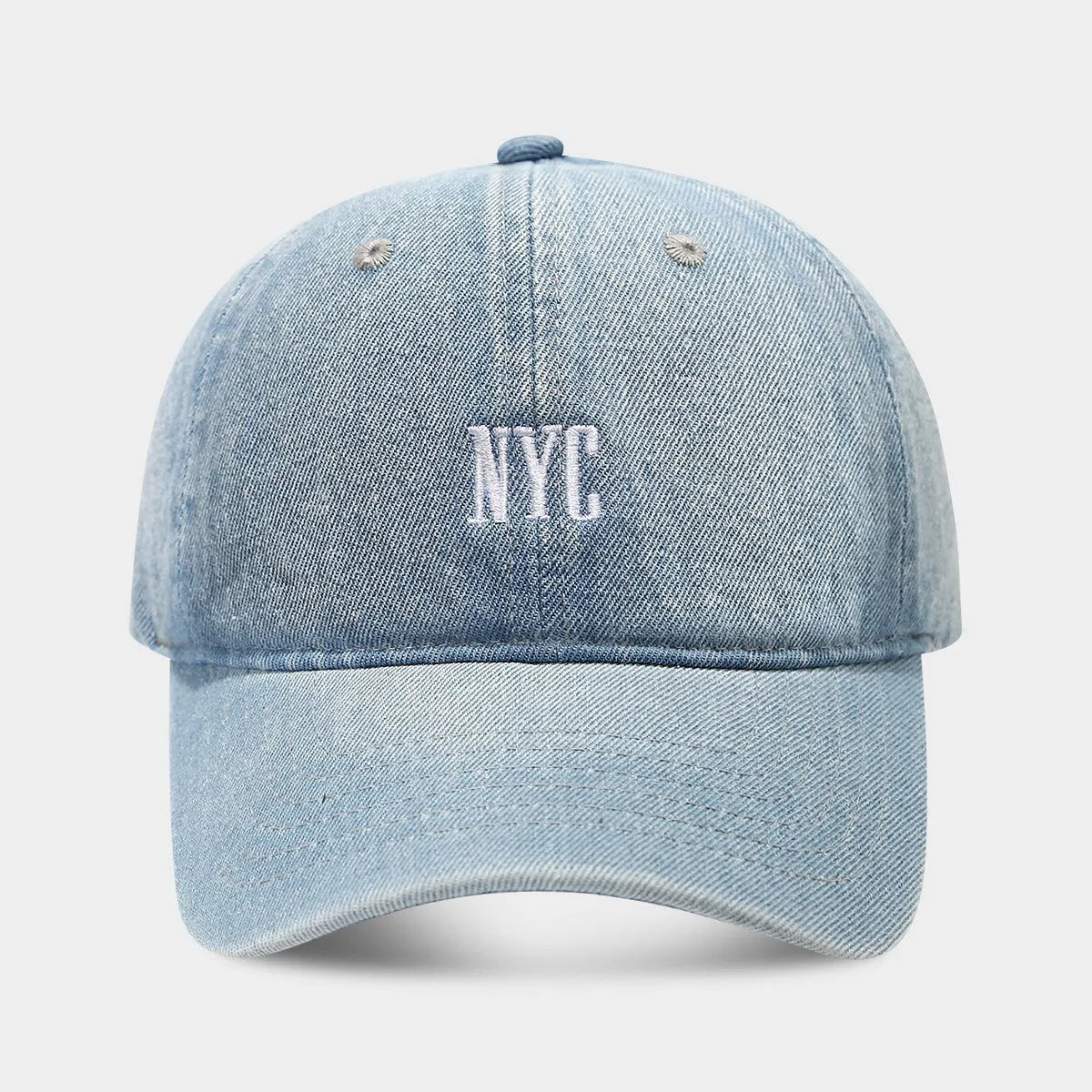 A light blue denim peaked cap with a dome crown, adjustable strap, and decorative white English letters on the front.