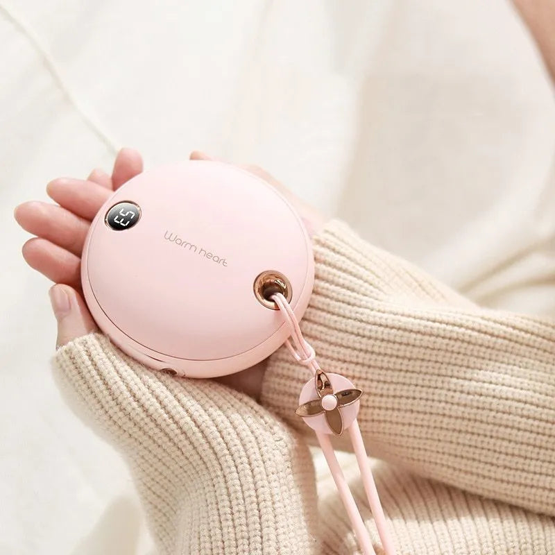 Green, pink, or white square 5000mAh hand warmer power bank with digital display next to charging cable.