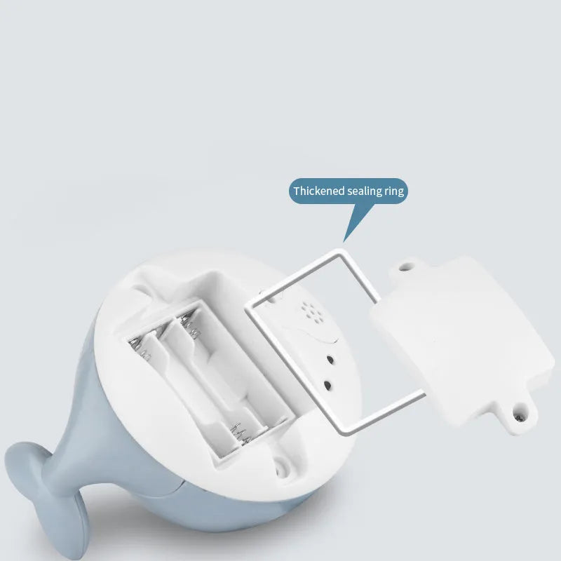 Whale-shaped electric bath toy spraying water with flashing lights, floating in baby bathtub