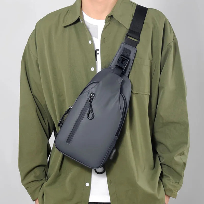 Black sling crossbody chest bag for men with zipper closure and stitched detail on a white background