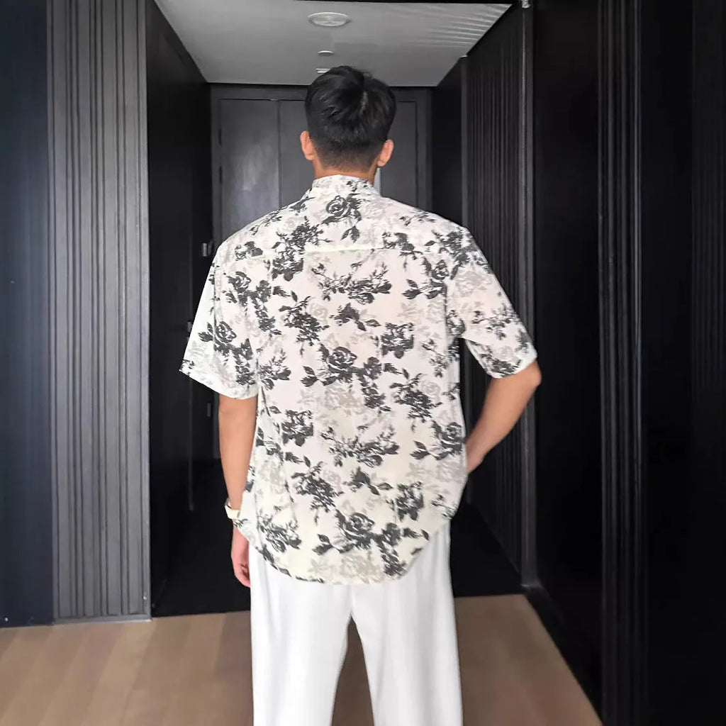 Loose-fitting floral print short sleeve shirt cardigan in black, laid flat.