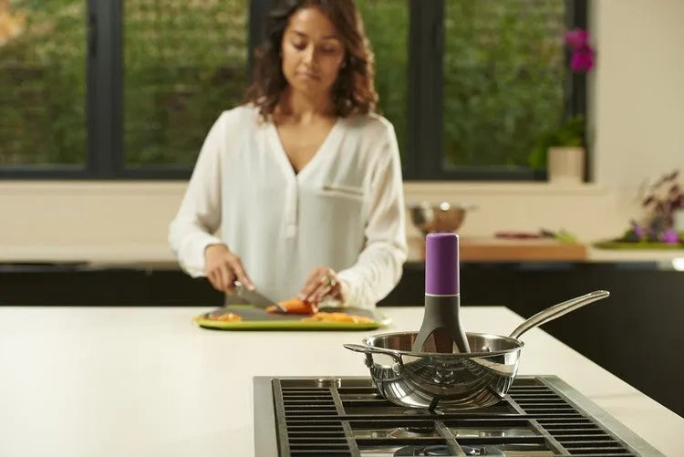 Green Uutensil Stirr automatic cooking mixer device next to a cooking pot.