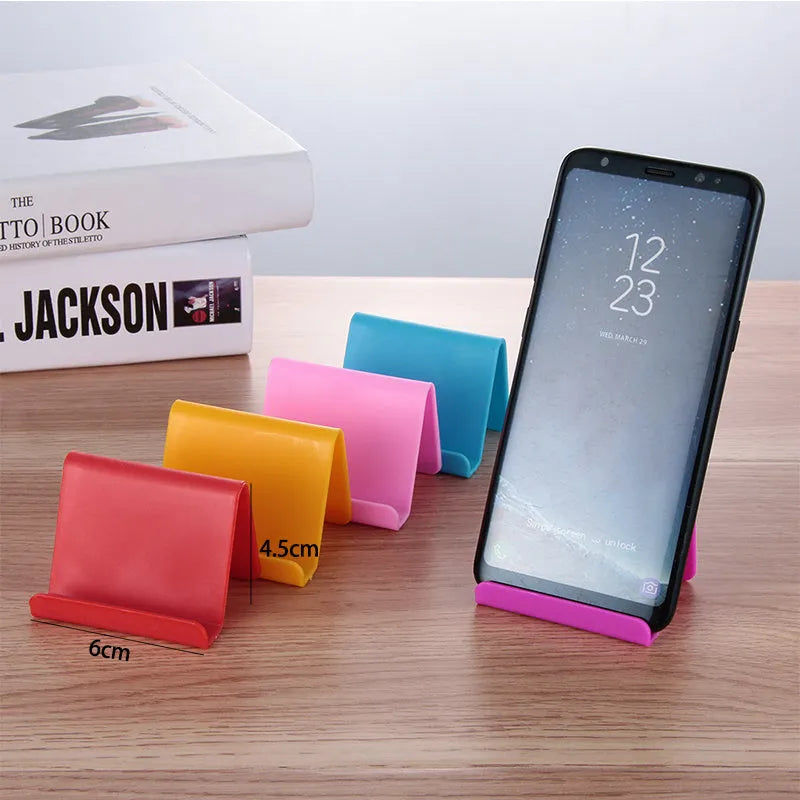 Small plastic mobile phone stand in blue, size 6x4.5cm, on a wooden desk