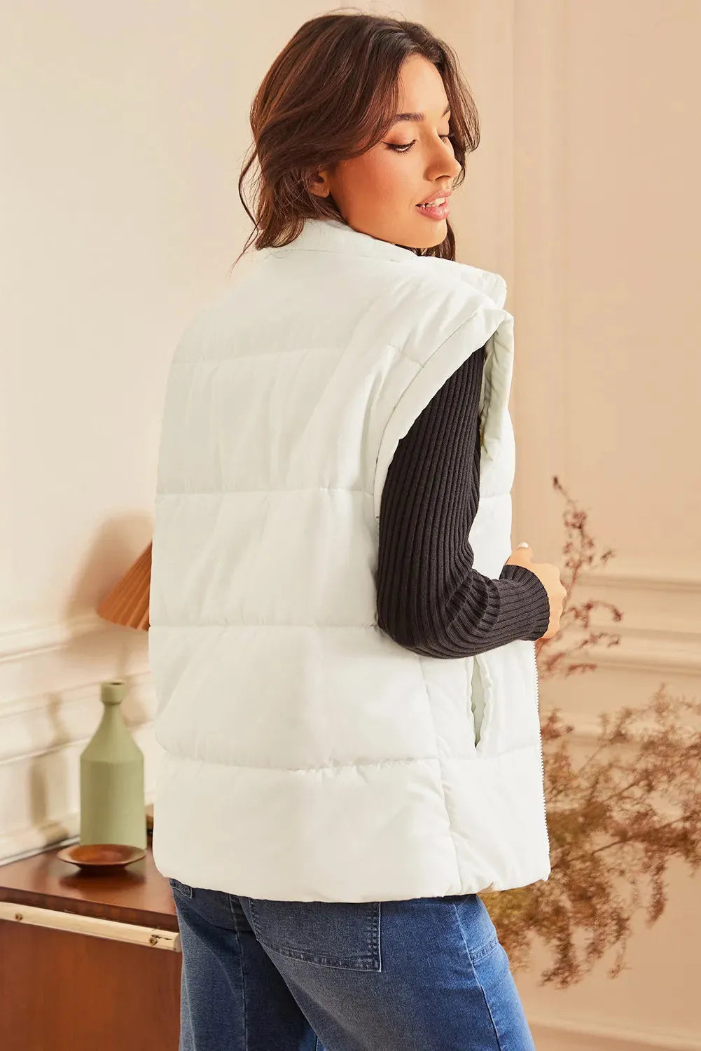 Women's beige oversized puffer vest with stand neck and front zipper, made from polyester, shown on a model