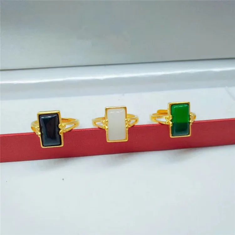 A gold-coloured adjustable ring with a large central green artificial gemstone, showing the national style design.