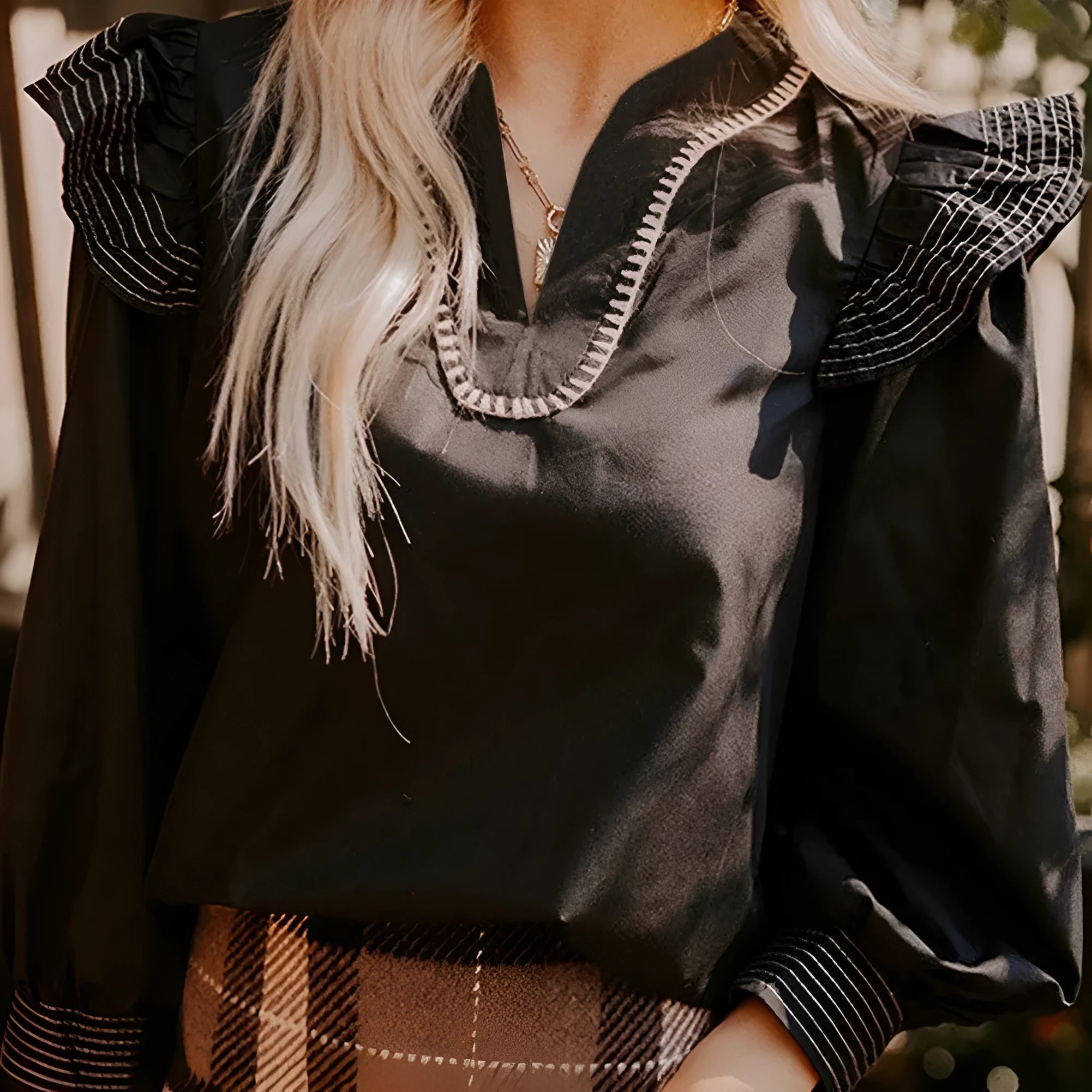 Black V-neck long sleeve blouse with contrast stitching and ruffle detail on sleeves.