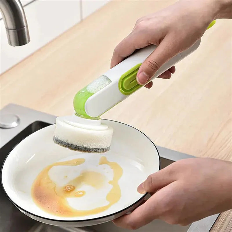 White and red long-handle kitchen brush with liquid dispenser button and two removable brush heads.