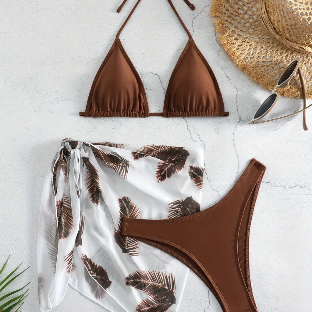 Orange three-piece bikini swimsuit set with a matching printed gauze skirt laid flat.