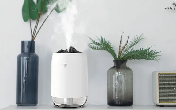 Mini cylindrical USB ultrasonic humidifier in white, pink, or green with warm night light on.