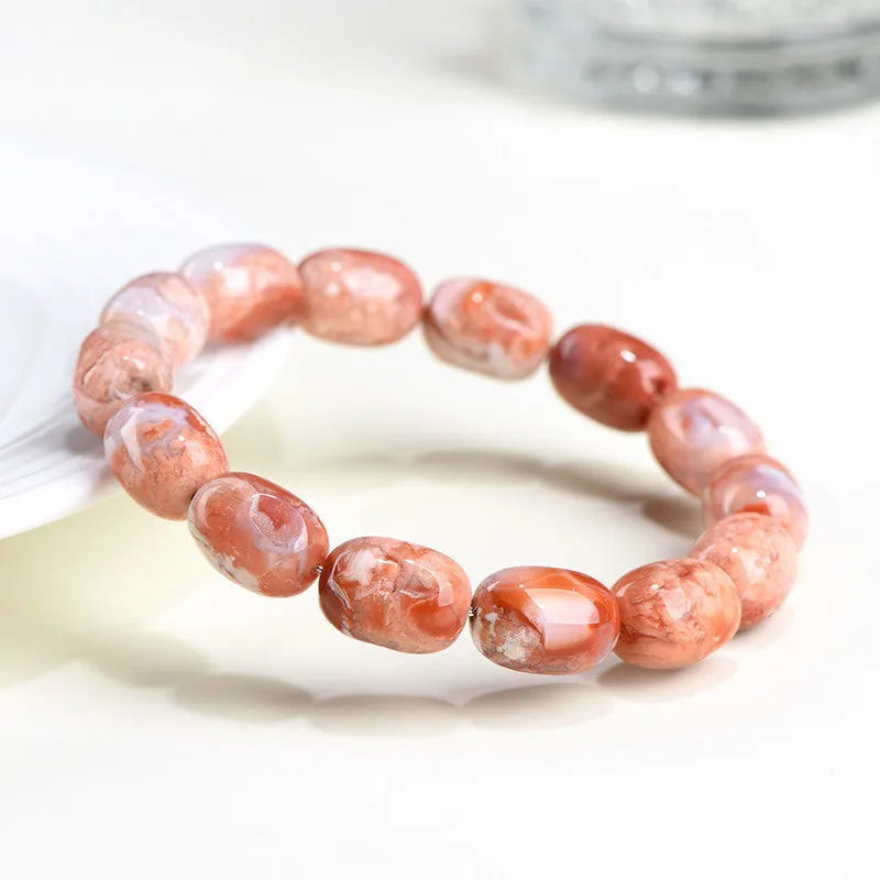 Natural cherry agate barrel bead bracelet with Ruyi symbol on a wrist.