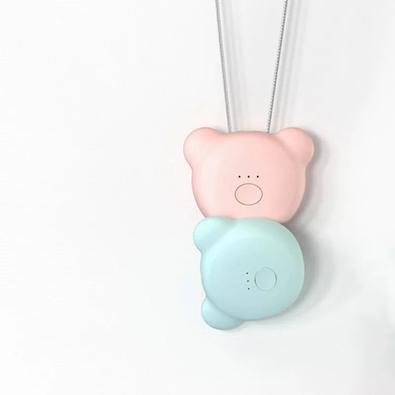 Compact pink USB portable air purifier necklace on a table with charging cable.