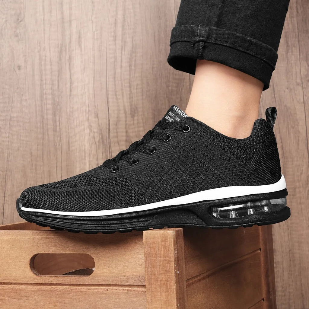 Pair of grey and black Flyknit mesh running shoes with a round toe and PU sole on a white background.