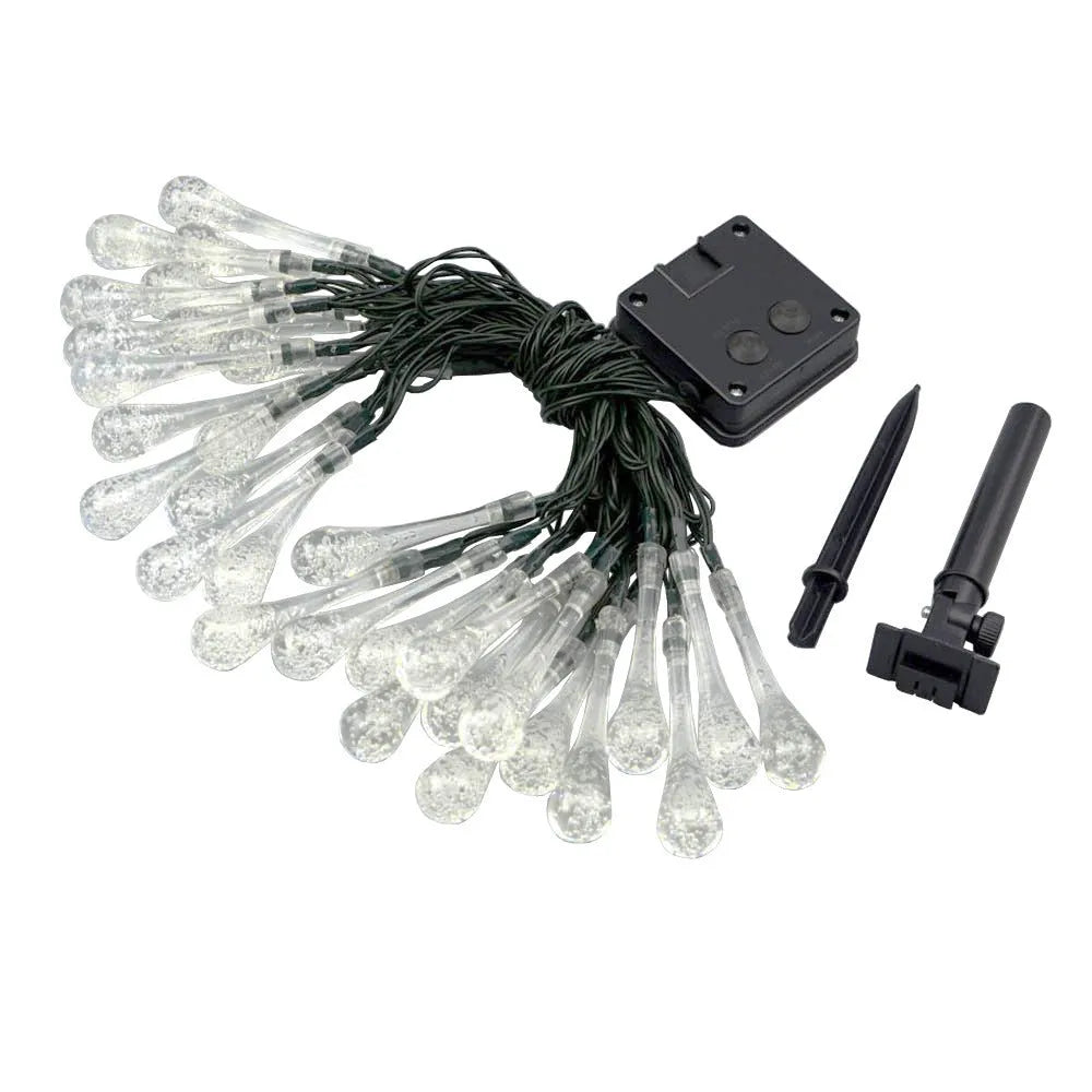 Water drop shaped solar LED fairy lights hanging outdoors with solar panel and ground spike.