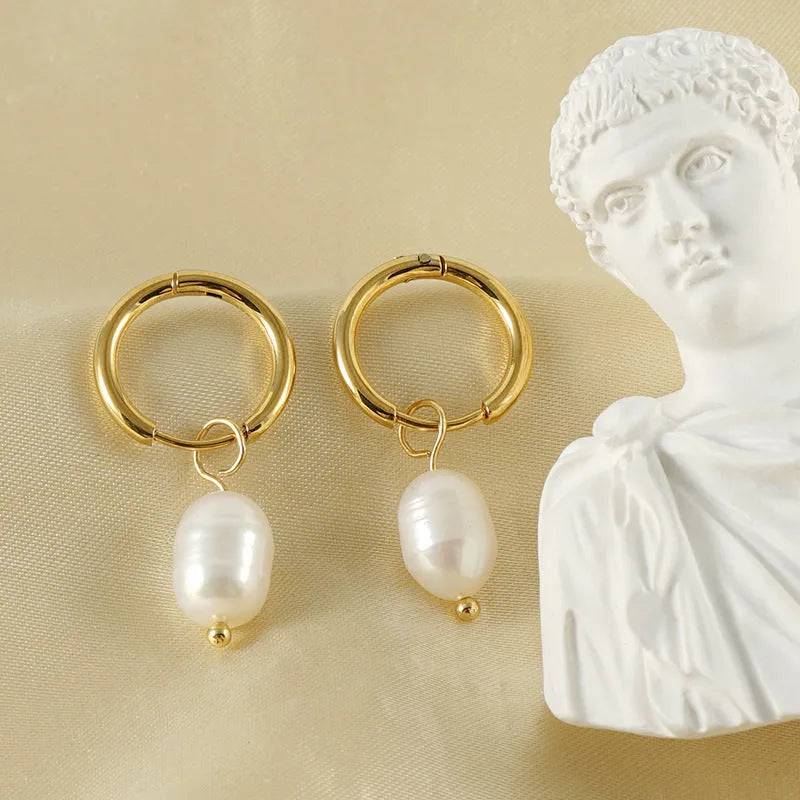 Geometric gold-coloured stainless steel earrings with a white pearl detail on a white background.