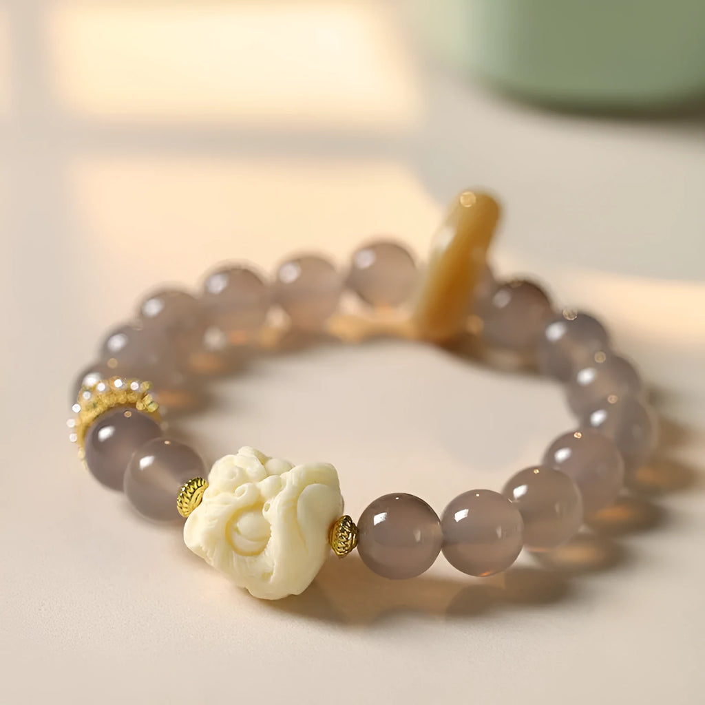 Hand-woven bracelet with 10mm round grey agate and mellite beads on a wrist.
