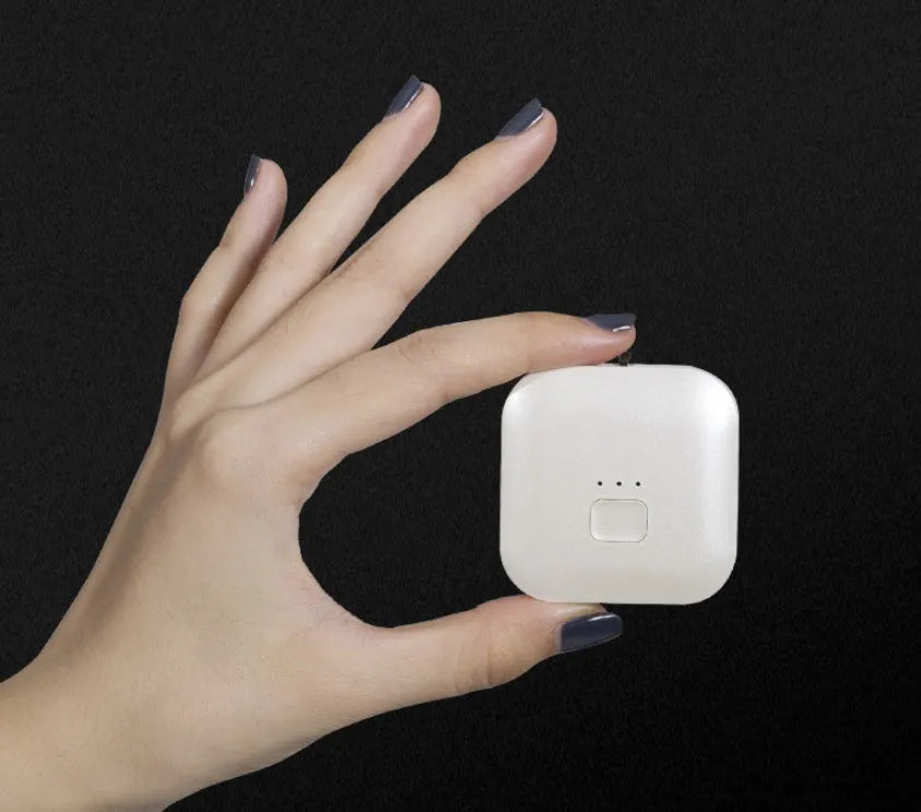 Compact pink USB portable air purifier necklace on a table with charging cable.
