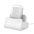 White headphone charging base station on a desk, holding a pair of over-ear headphones.