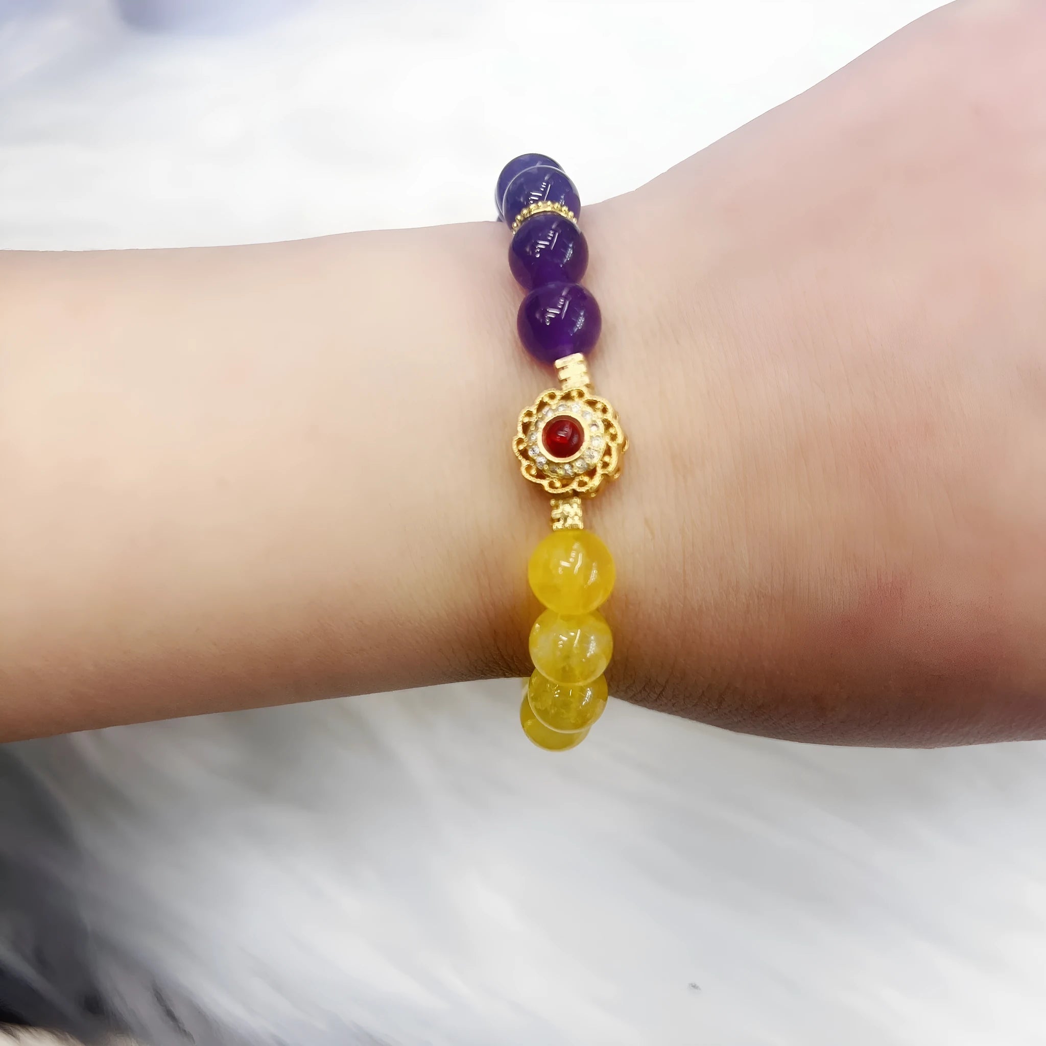 Handmade women's yellow and purple amethyst crystal bracelet showing manual craftsmanship detail