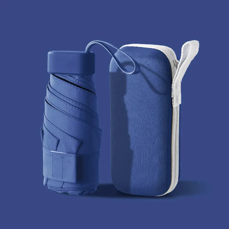 Ultra-light six-fold flat sun umbrella in sky blue with a rubber handle, shown with its capsule storage box.