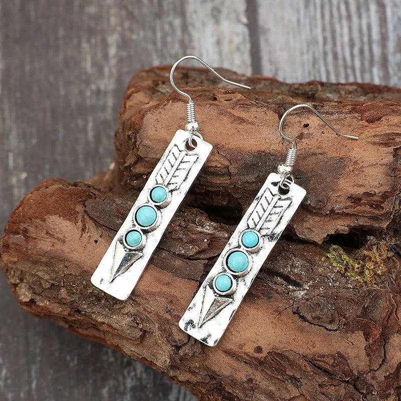 Silver geometric drop earrings with turquoise inlays and retro styling on white background