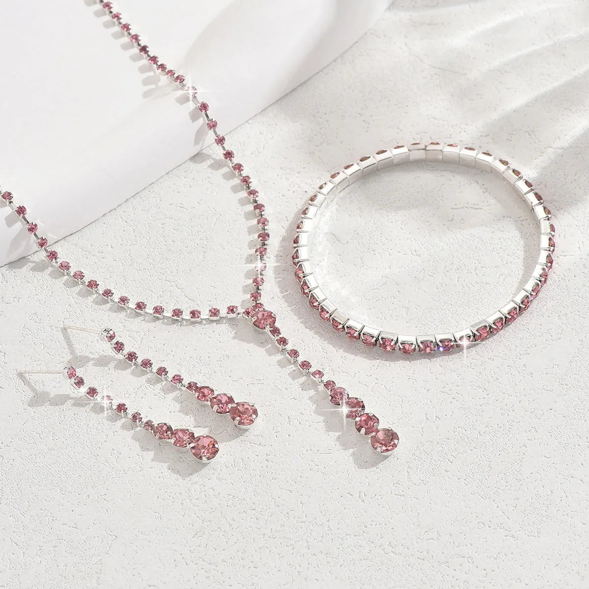 Three-piece bridal jewellery set showing necklace, bracelet and earrings with rhinestone pendant and heart-shaped design