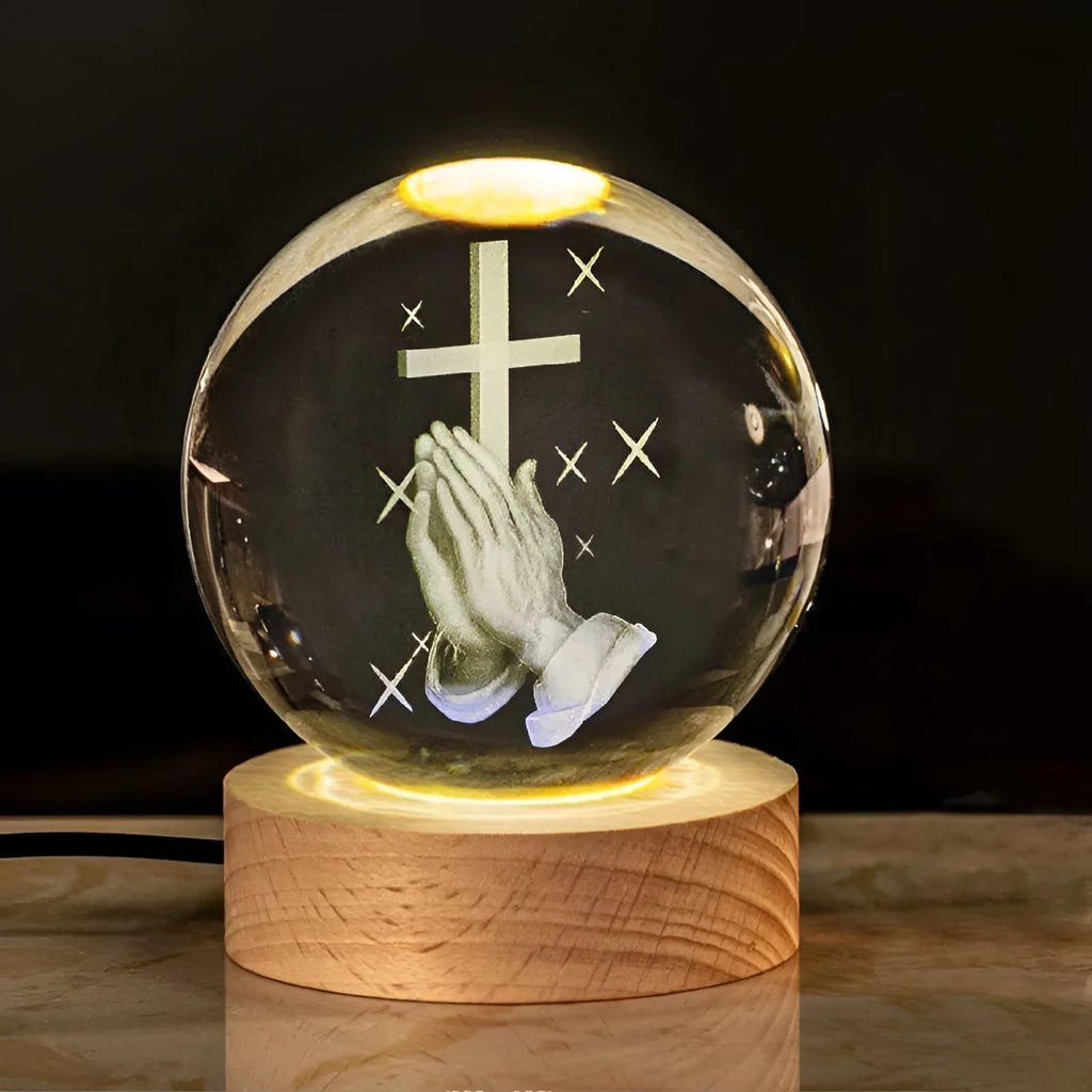 White crystal ball ornament with internal Christian cross figure on a wooden light-up base.