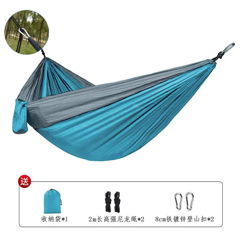 Blue parachute nylon outdoor hammock hung between two trees in a garden setting