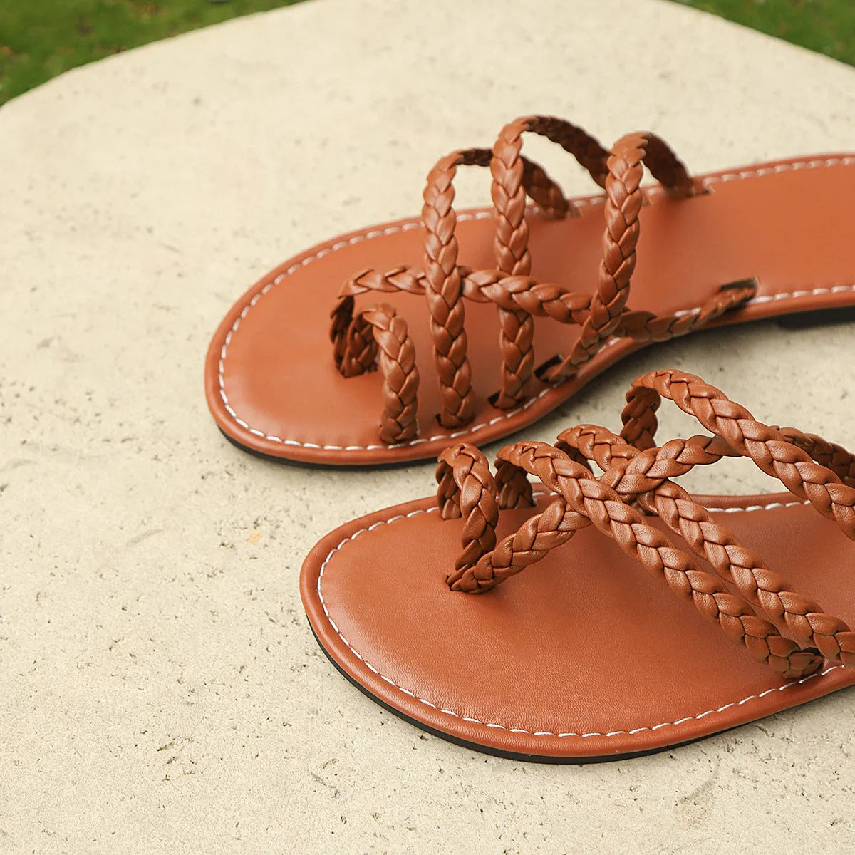 Women's woven flat sandals with a clip-toe design in black, white, or brown.