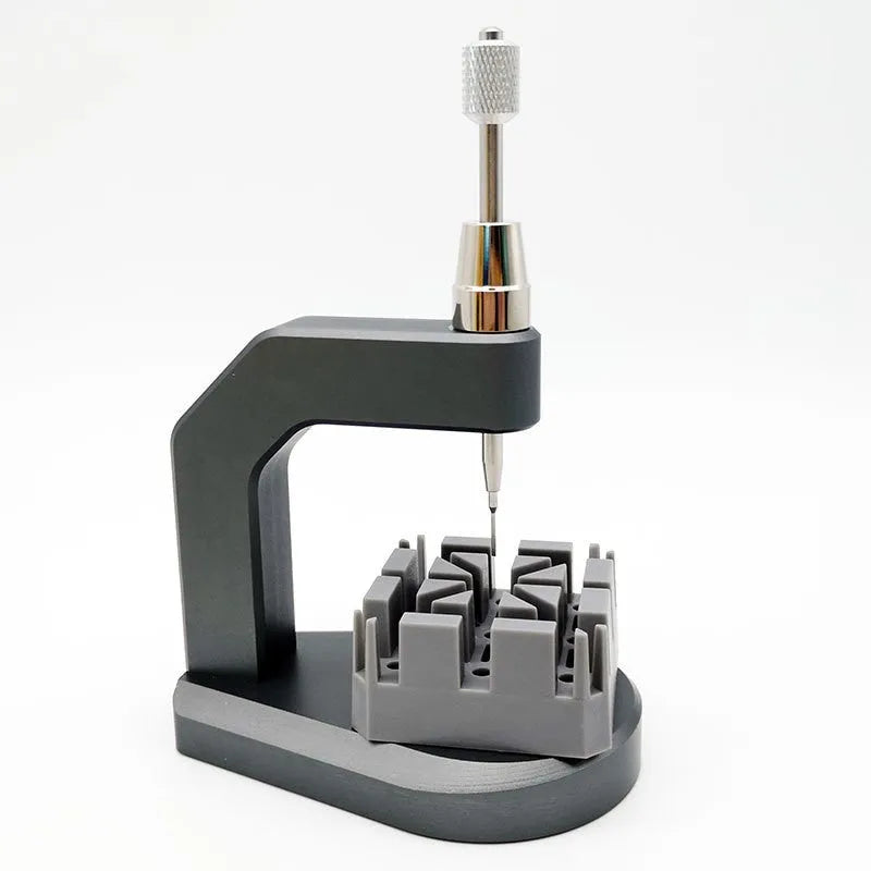 Silver tool steel multi-purpose press strap removal tool on a work surface.
