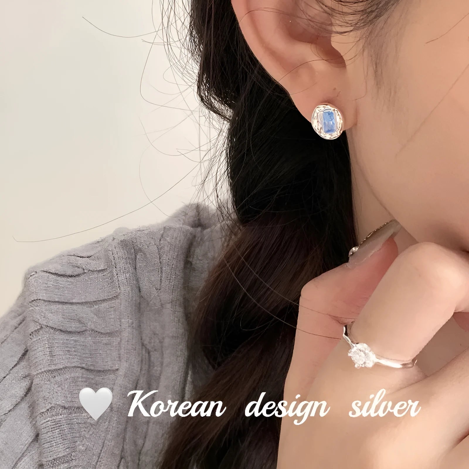 Women's sterling silver oval earrings with heart-wrapped design and blue diamond accents on silver background