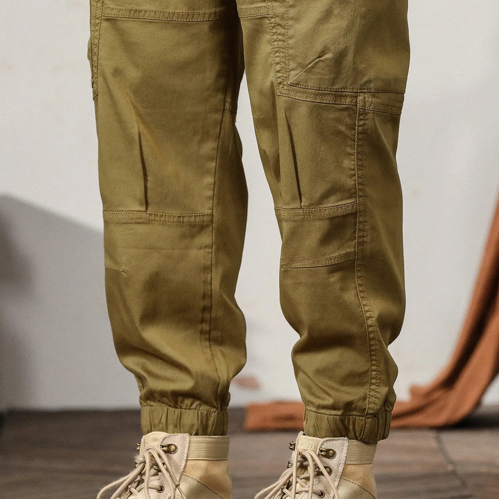 Man wearing khaki loose-fit cotton harem pants with tapered ankle-banded legs.