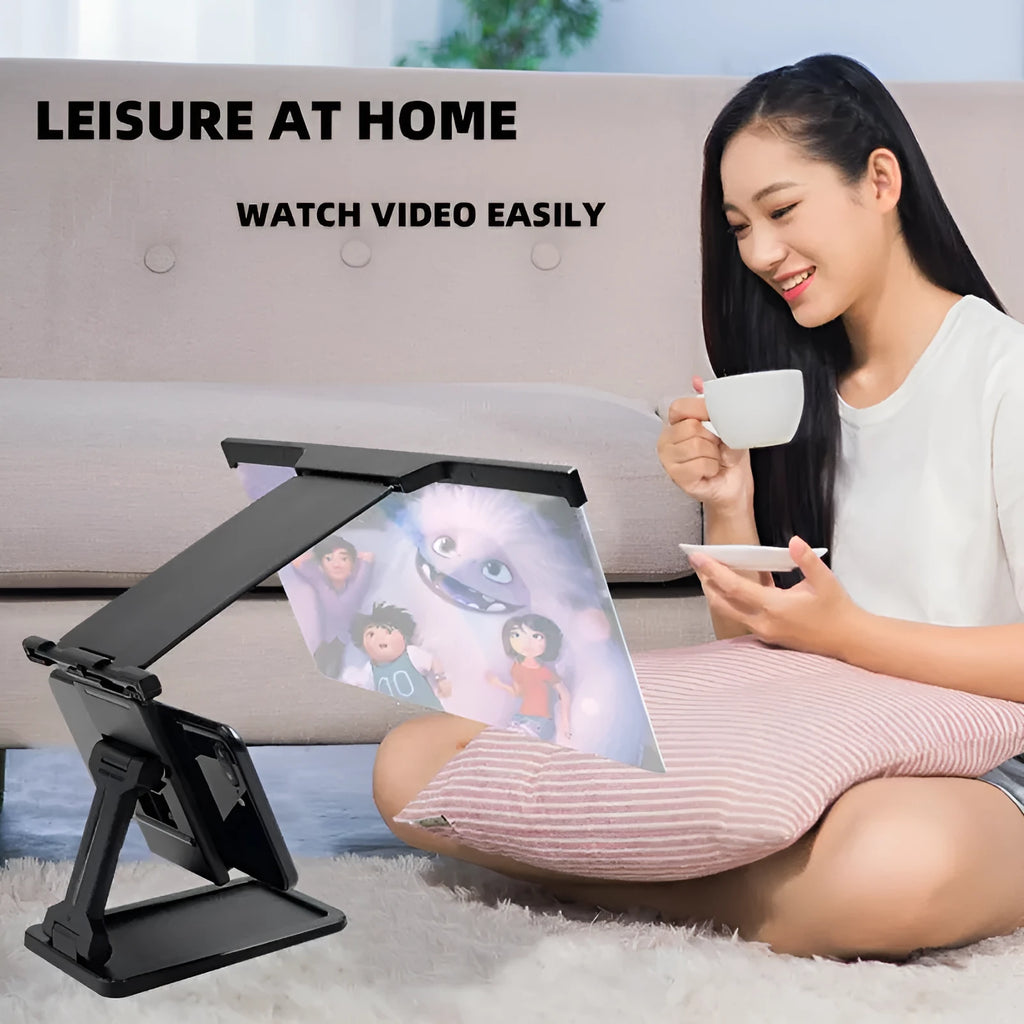 Black foldable mobile phone screen amplifier with a detachable phone holder on a desktop.
