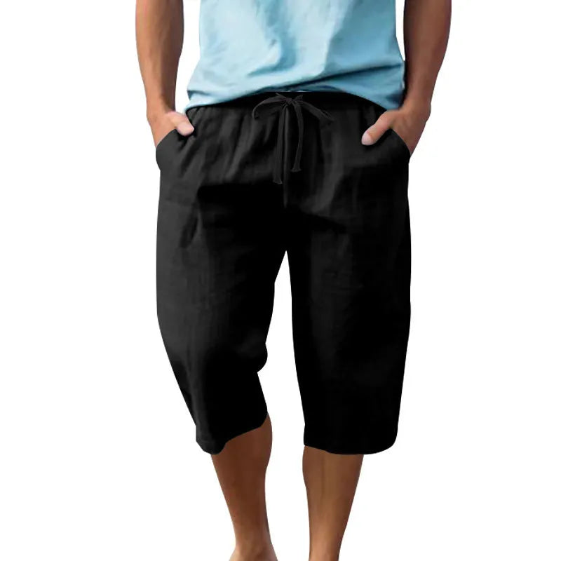 Man wearing loose, high-waisted linen shorts in a solid colour with a drawstring waist.