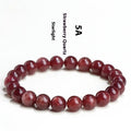 Natural cherry red strawberry quartz bracelet with geometric beads on a wrist.