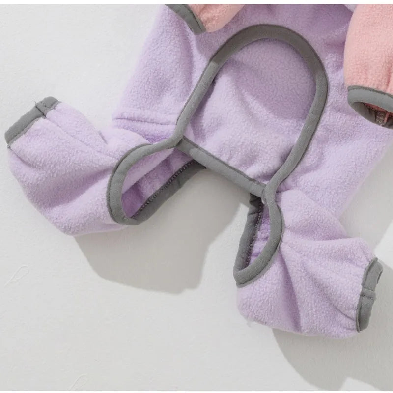 Small dog wearing a colour-block fleece jumpsuit in purple and pink, with full-zip front and leash ring