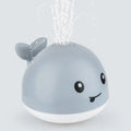 Whale-shaped electric bath toy spraying water with flashing lights, floating in baby bathtub
