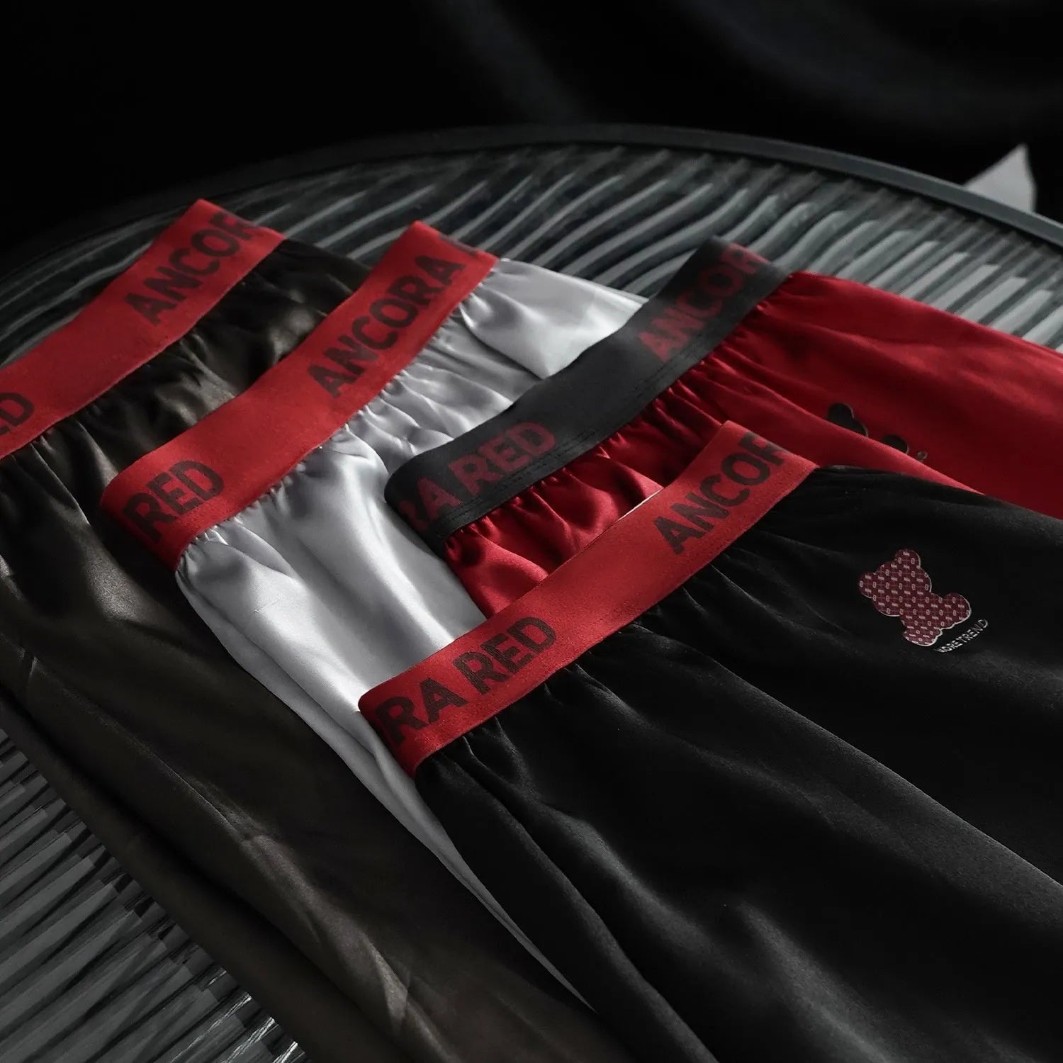 Solid colour men's polyester boxer briefs on a mid-waist, shown in black, blue, brown, purple, red, and silver.