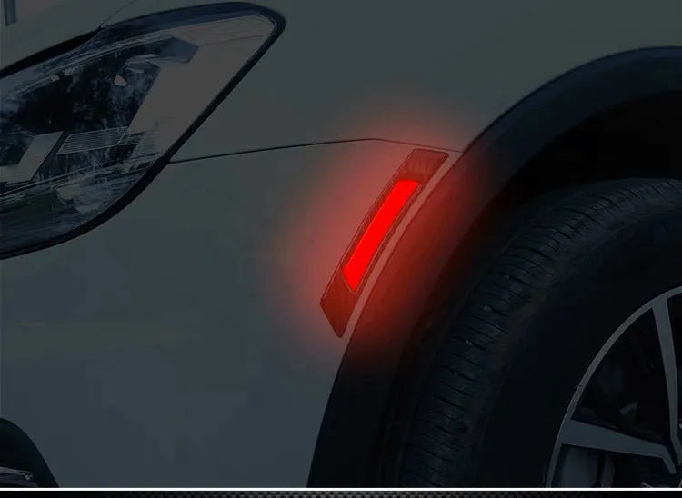 Set of four fluorescent reflective car wheel brow adhesive strips in blue, red, white, and yellow on a black car wheel arch