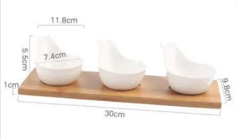 Porcelain ceramic dried fruit dish with three snack compartments on a wooden serving board.