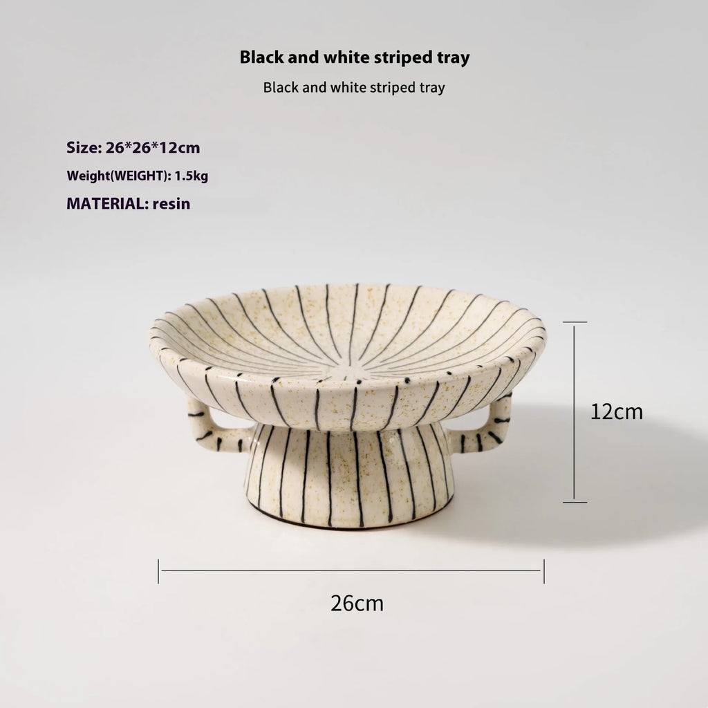 Black and white striped synthetic resin fruit plate on a wooden surface.