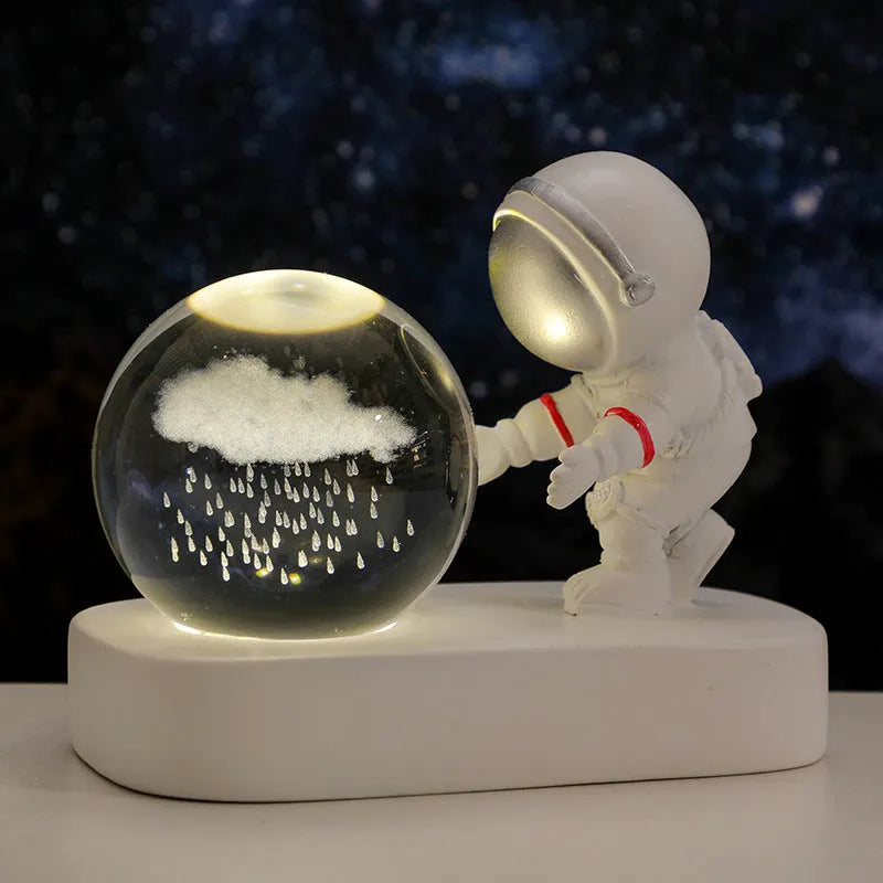 Small clear resin ball night light with glowing astronaut and galaxy scene inside on dark surface