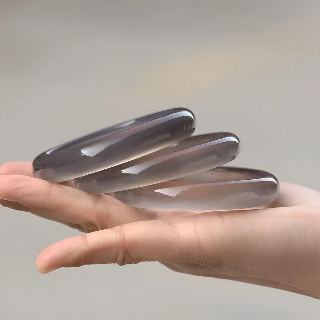 Close-up of a dark grey Brazilian agate bracelet showing circle and line patterns on the stone.