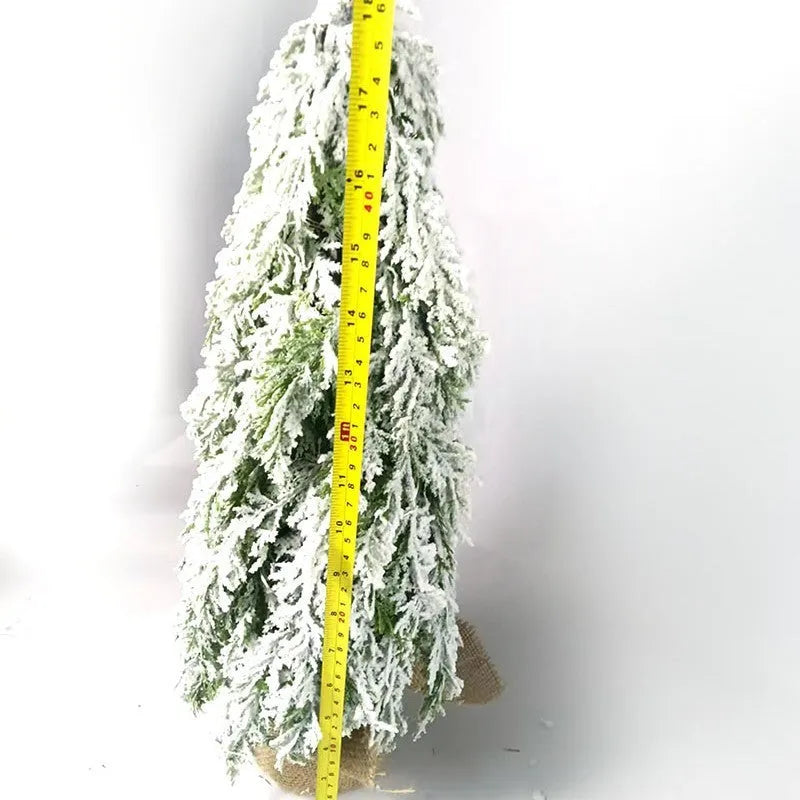 Small 24-inch artificial Christmas tree with lights and snow finish on desktop