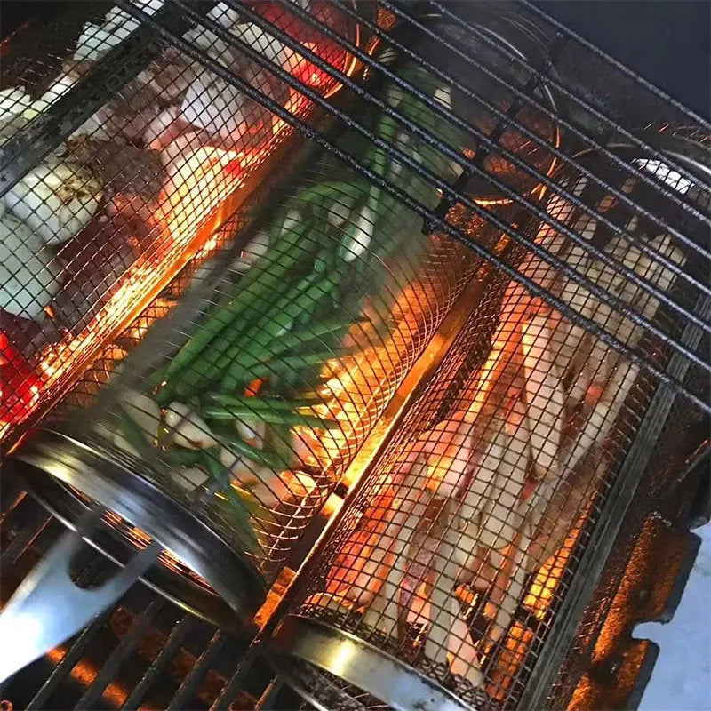 Round silver metal rolling barbecue basket with wire mesh and a hook, shown with vegetables inside on a grill.