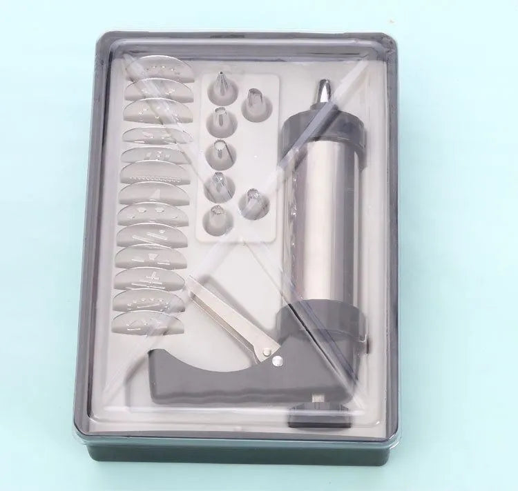 Stainless steel biscuit press gun with assortment of cookie moulds and piping nozzles on a baking sheet.