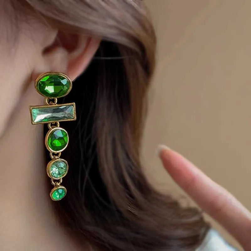 A pair of green gradient geometric drop earrings with inlaid zircon stones and a dangling tassel detail.
