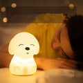 White silicone puppy-shaped LED night light with soft glow on a flat surface